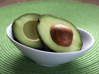 An avocado, sliced in half, in a white bowl