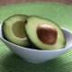 An avocado, sliced in half, in a white bowl