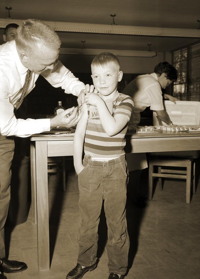 This 1962 image depicts a schoolboy receiving a measles vaccination CDC