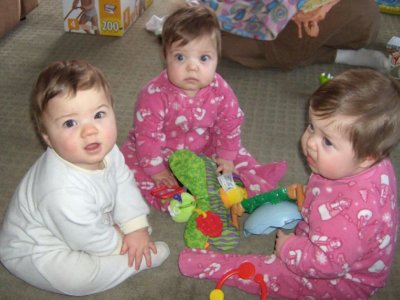 Three toddler triplets sitting on rug