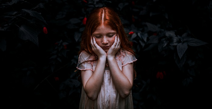 Girl holding her head, with hands on her jawline