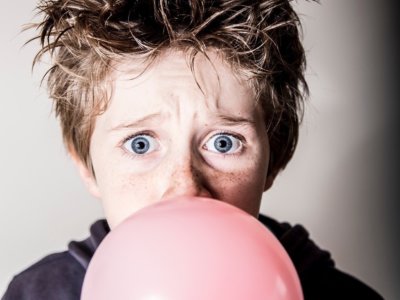 Concerned boy blowing large bubble