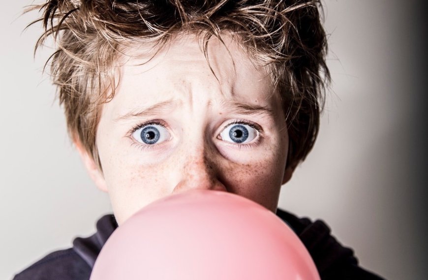 Concerned boy blowing large bubble