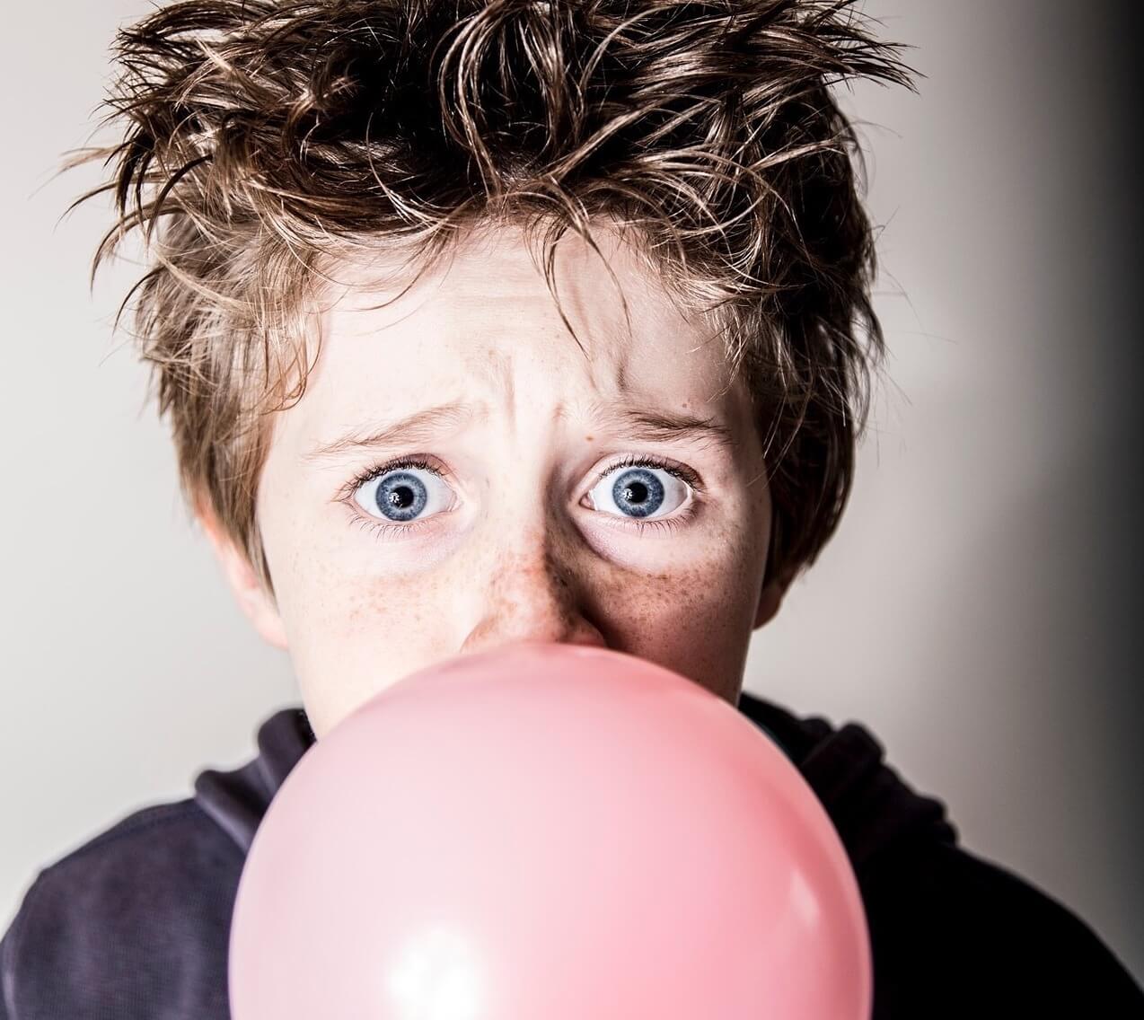 Concerned boy blowing large bubble